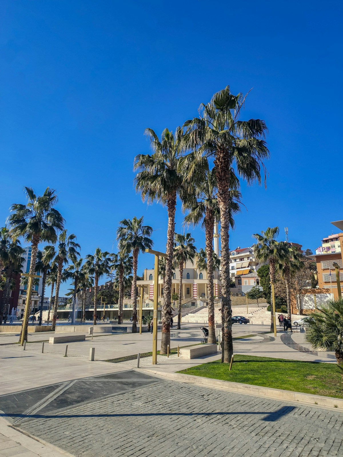 Town square in Durrës with tall palm trees and people, Albania