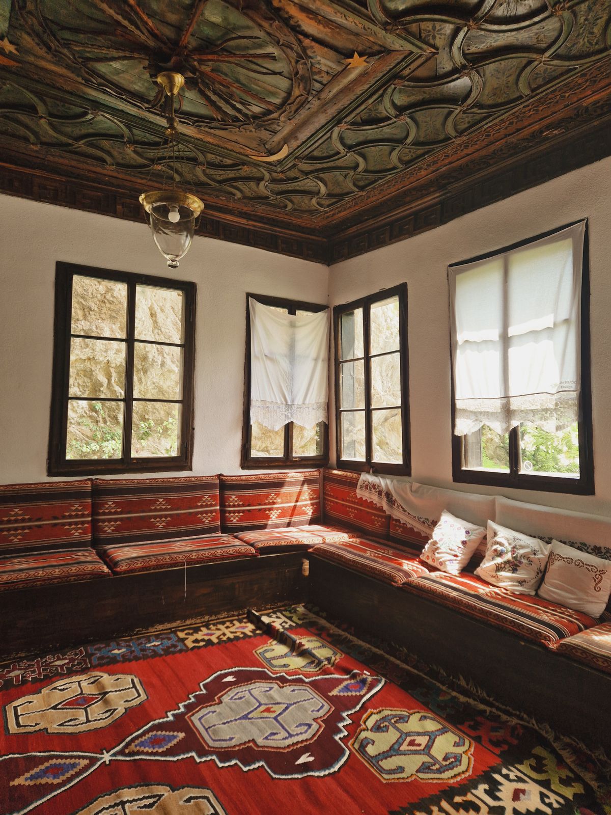 Traditional Bosnian sitting room with kilim carpets and ornate painted ceiling in Mostar