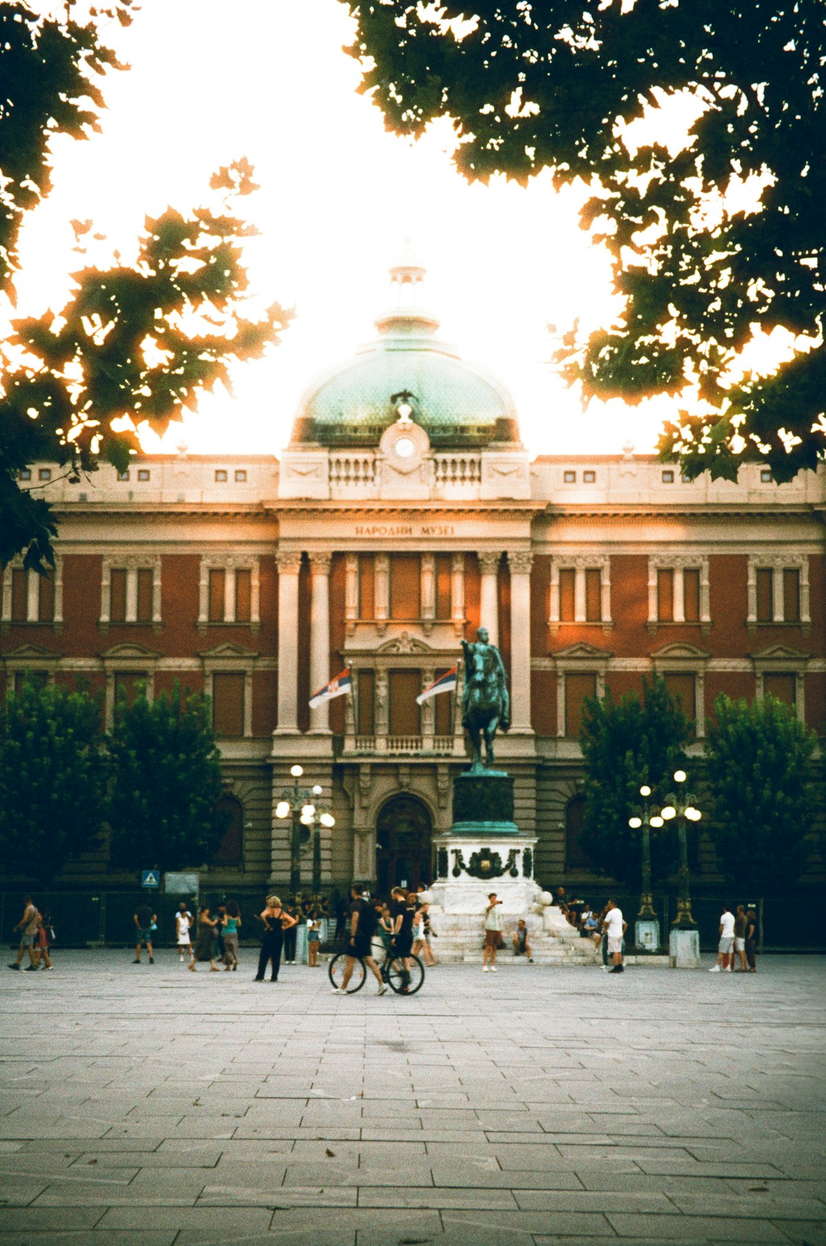 People gathered at a grand building at sunset, Belgrade, Serbia
