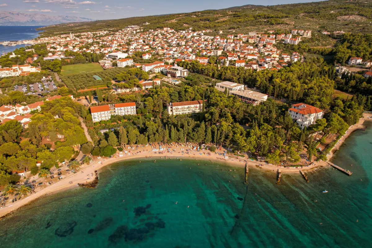 Aerial view of a coastal town on Brač island with turquoise water and hillside, Croatia