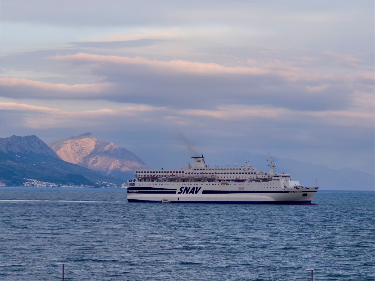 White ferry sailing on the Adriatic Sea with mountain backdrop, Croatia