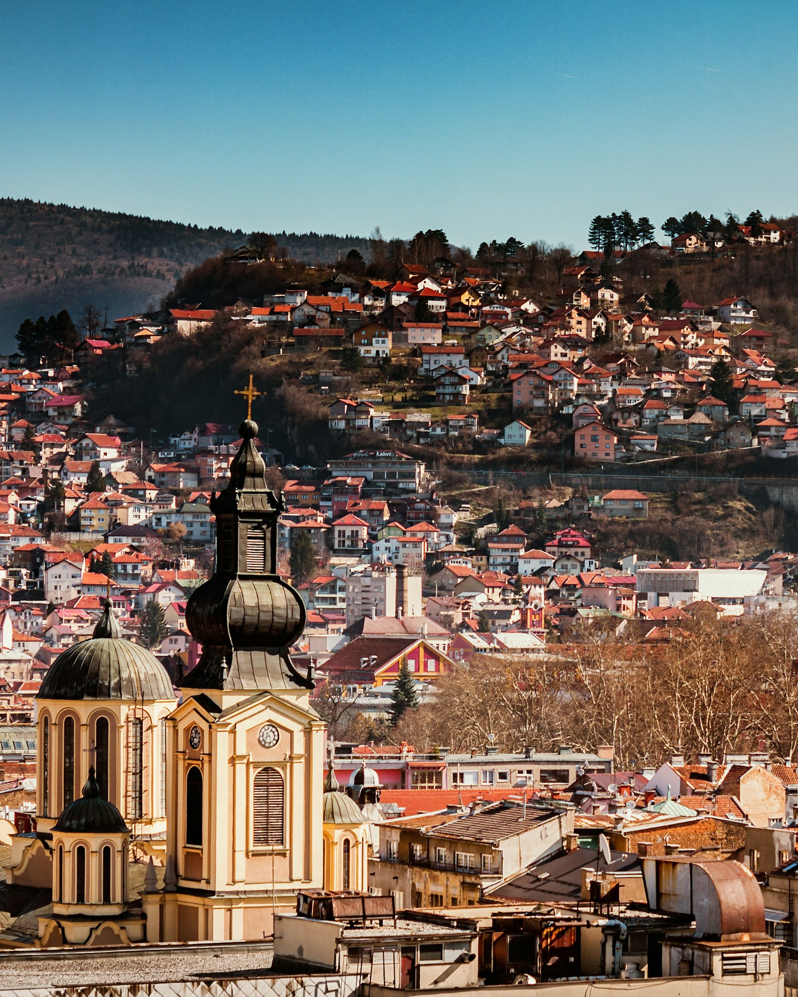 Sarajevo cityscape with mosque minarets and red-roofed houses on the hillside