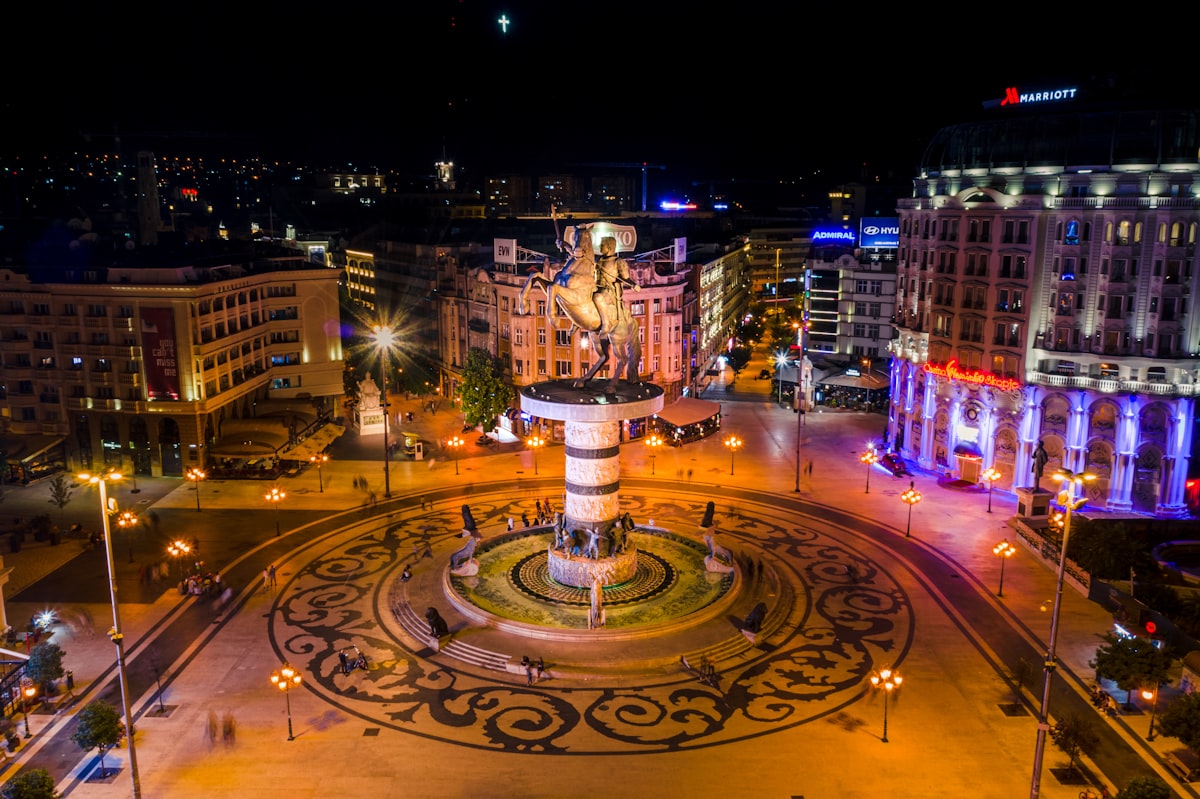 Warrior on a Horse fountain at Macedonia Square in Skopje at night, with illuminated Baroque-style buildings