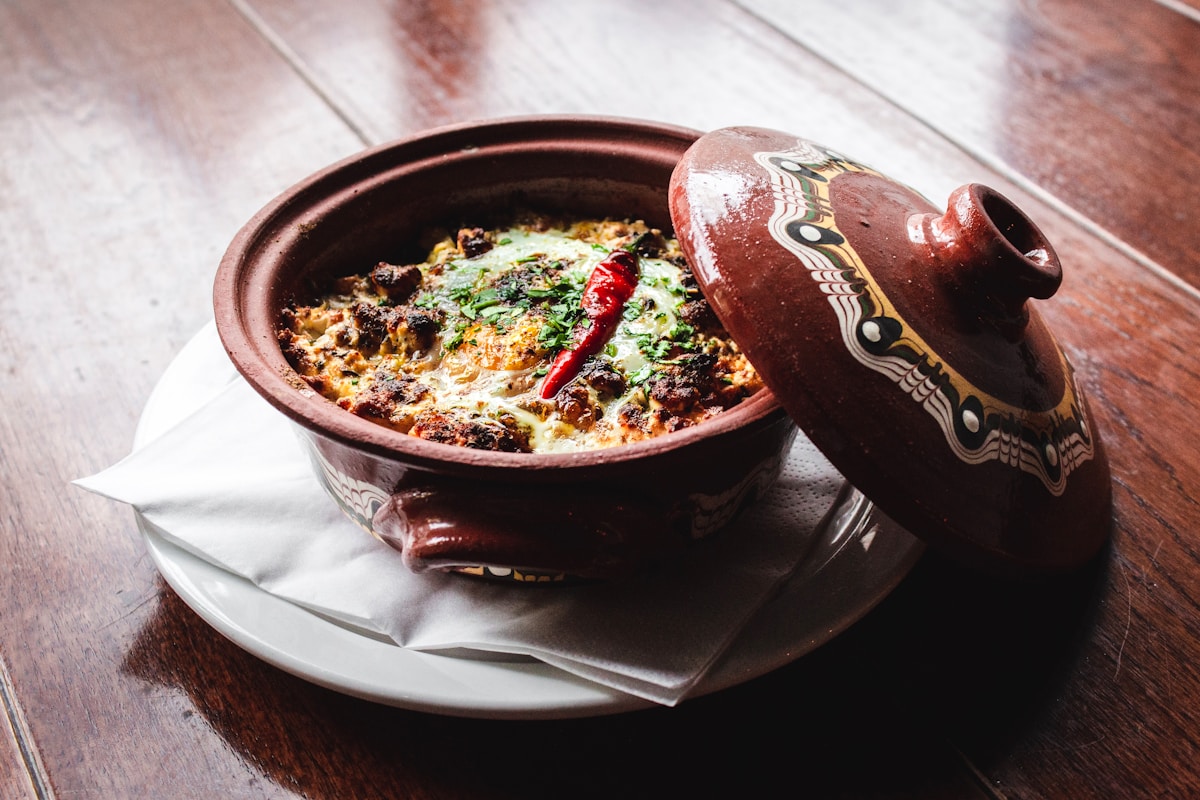 Clay pot with traditional Bulgarian kavarma stew on a wooden table