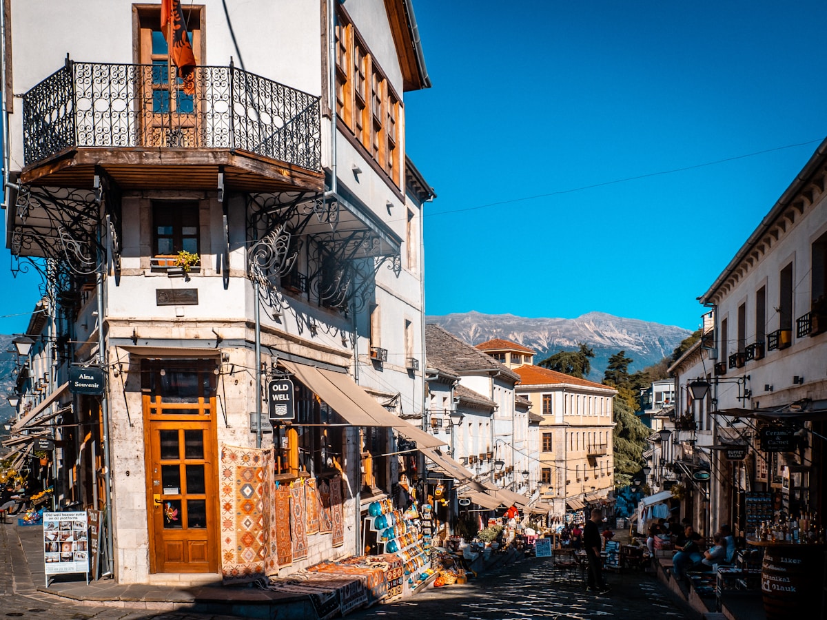 People walking past old stone buildings in Gjirokastër Bazaar, Albania
