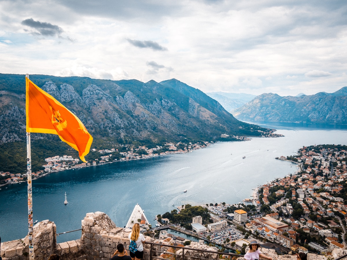 Montenegrin flag flying above Kotor old town with the Bay of Kotor and mountains behind