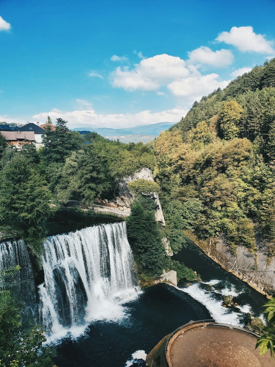 Waterfalls near green trees under blue sky in Jajce, Bosnia