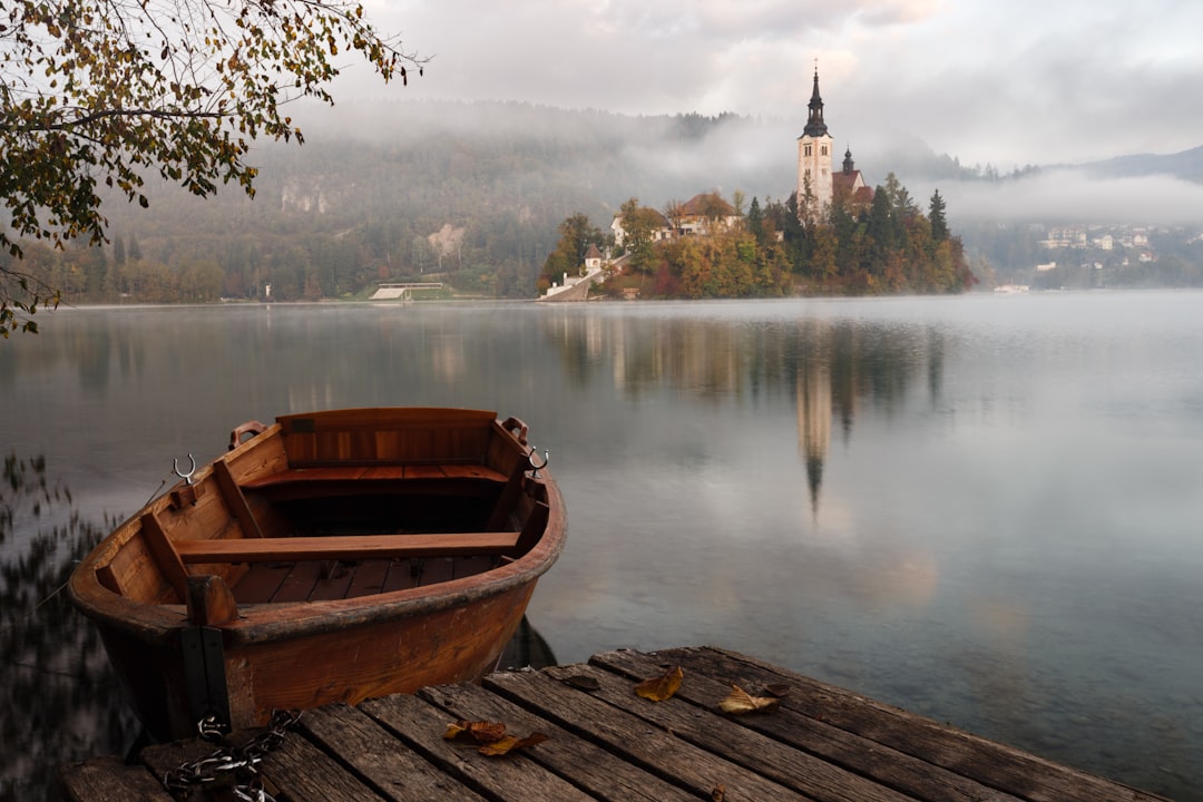 Wooden rowing boat moored on misty Lake Bled with church island and castle in Slovenia