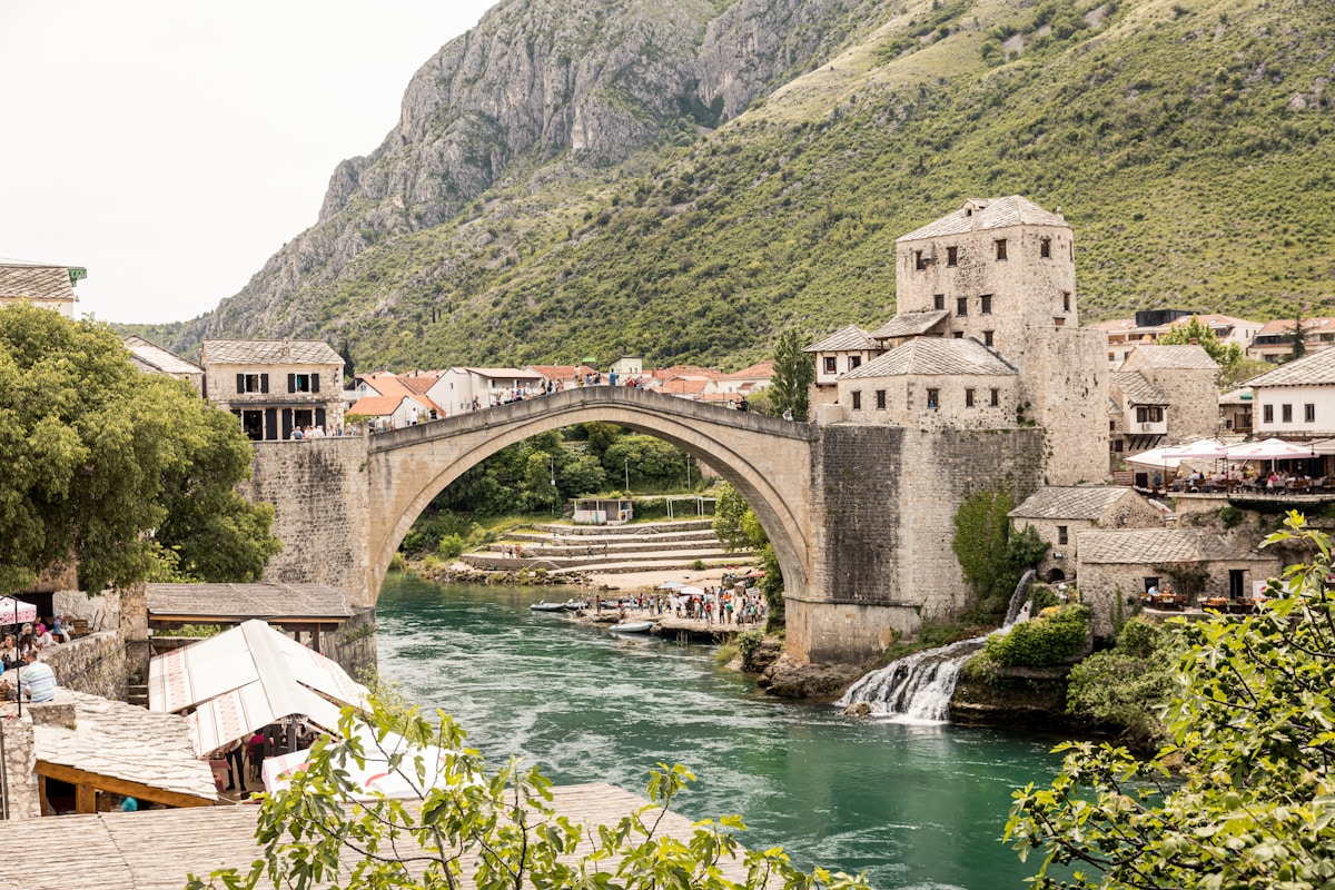 Stone arch bridge over a river with green trees, Mostar, Bosnia