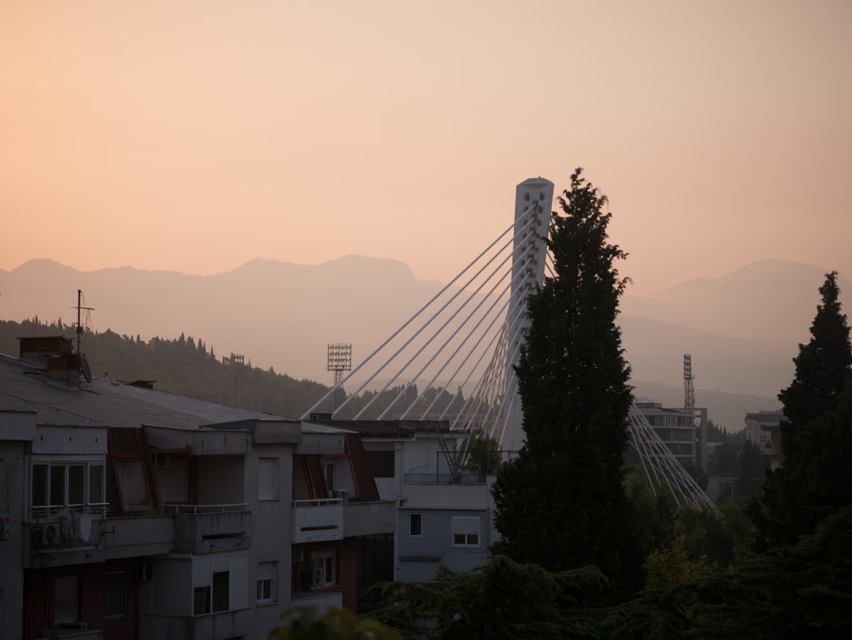 Podgorica skyline at dusk with the Millennium Bridge cable tower and mountains behind, Montenegro