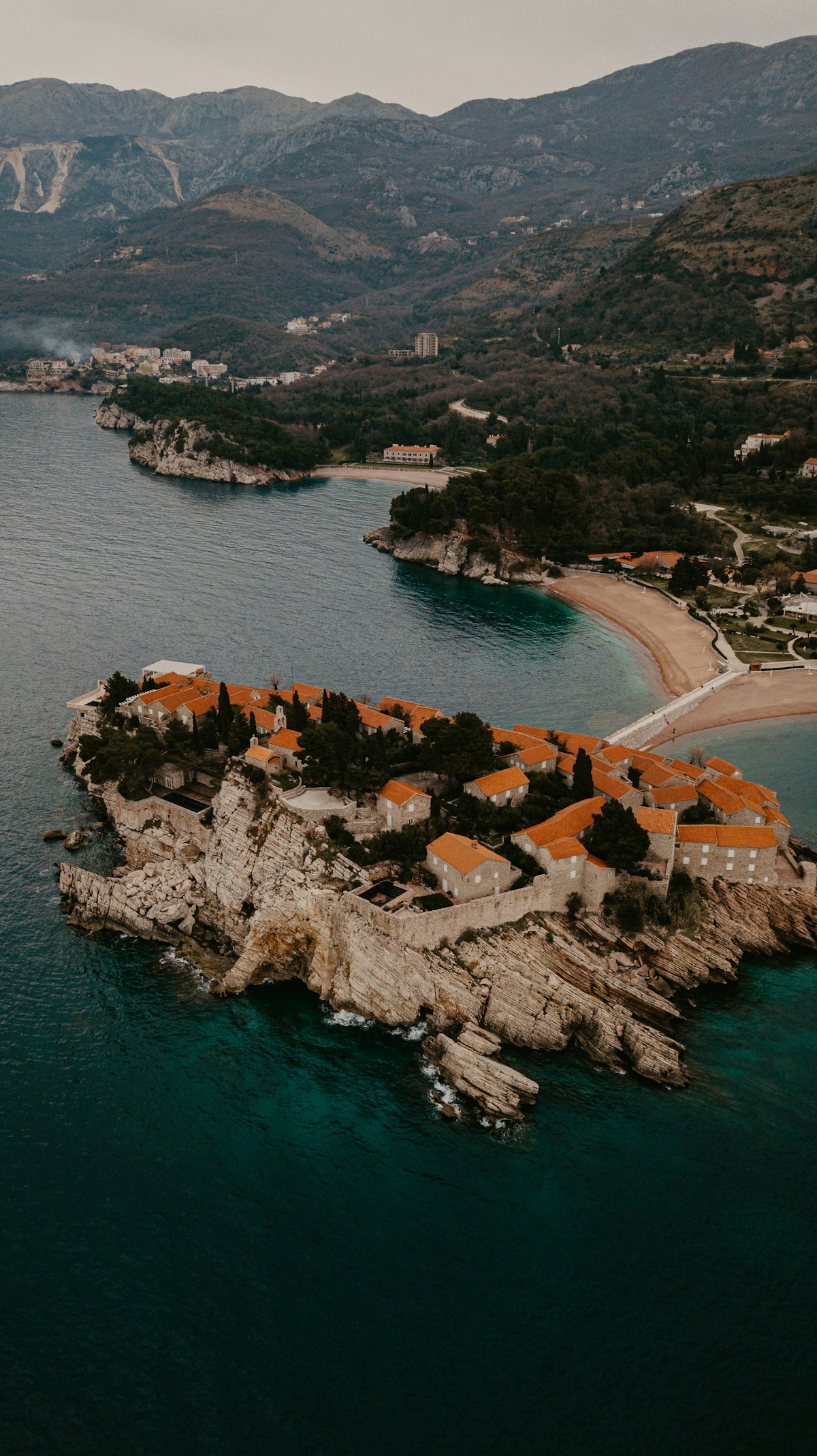 Aerial view of Sveti Stefan island resort with terracotta rooftops surrounded by turquoise Adriatic water, Montenegro