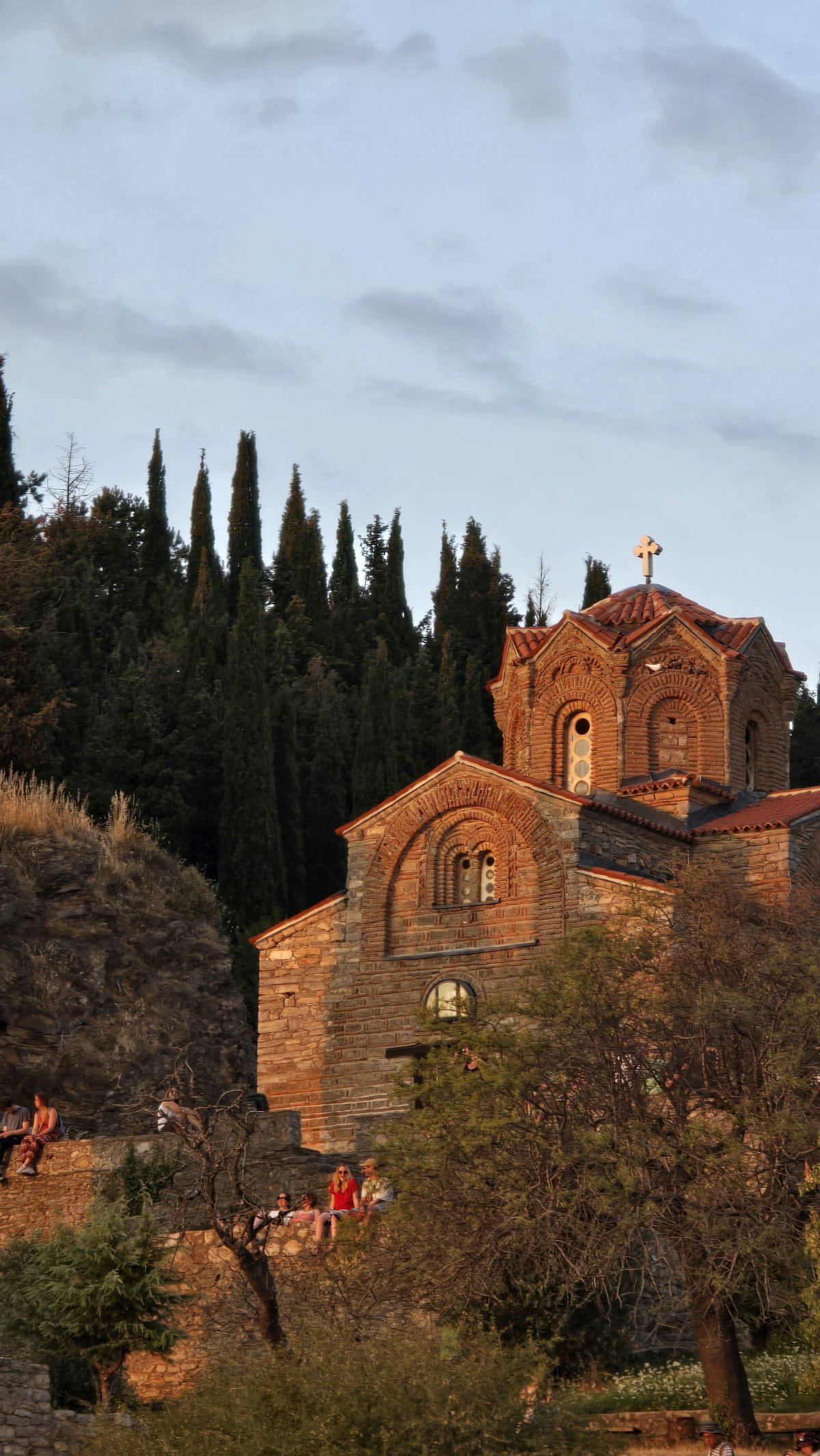 Ohrid church on hilltop with cypress trees and visitors below, North Macedonia