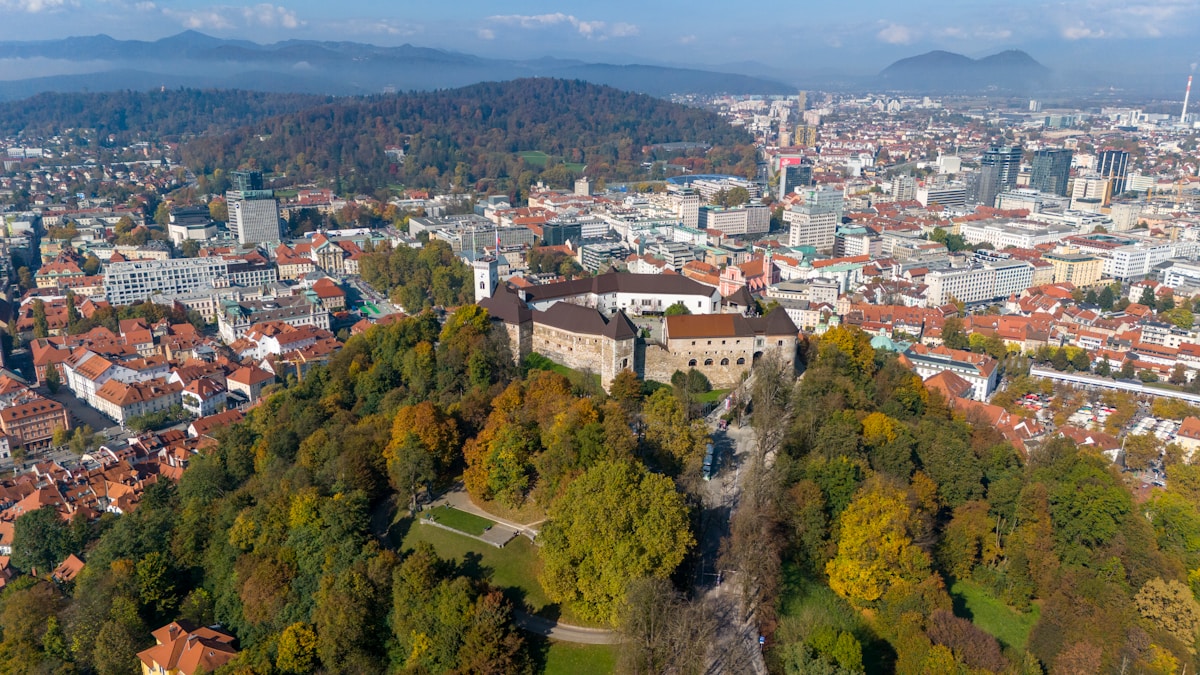 Aerial view of Ljubljana Castle on a forested hill overlooking the city with red-roofed buildings, Ljubljana, Slovenia