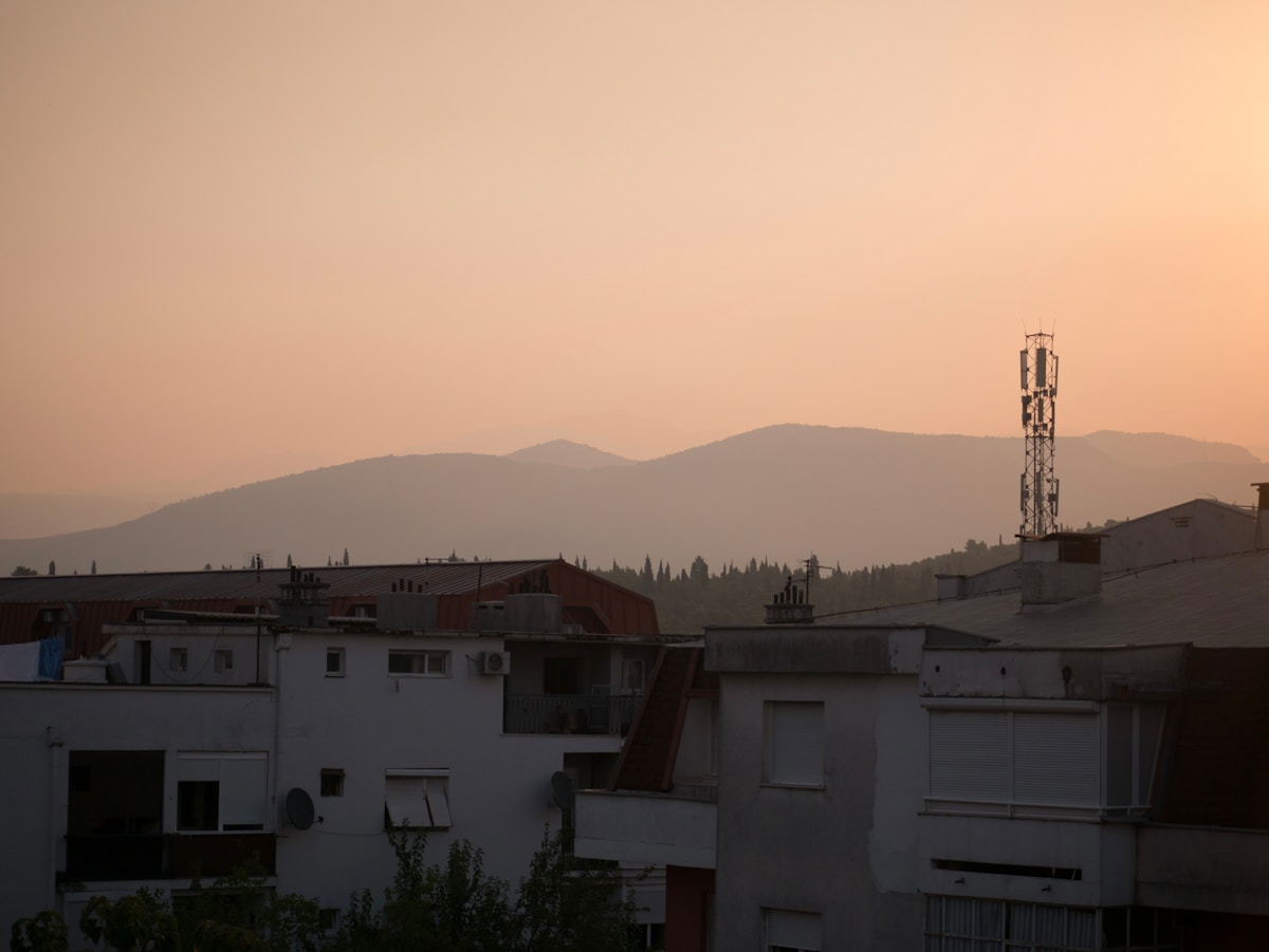 Podgorica rooftops at sunset with mountains silhouetted in the background, Montenegro