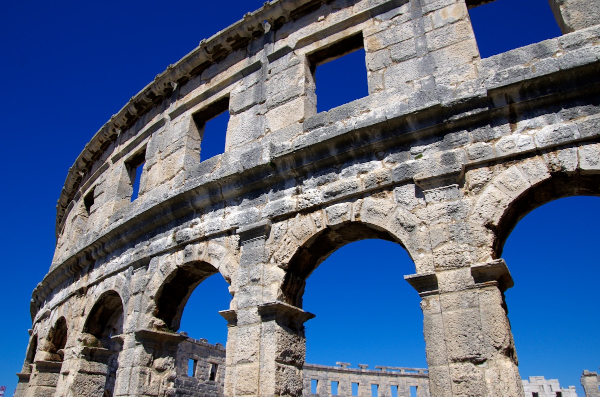 Exterior arches of Pula Arena under clear blue sky, Pula, Croatia