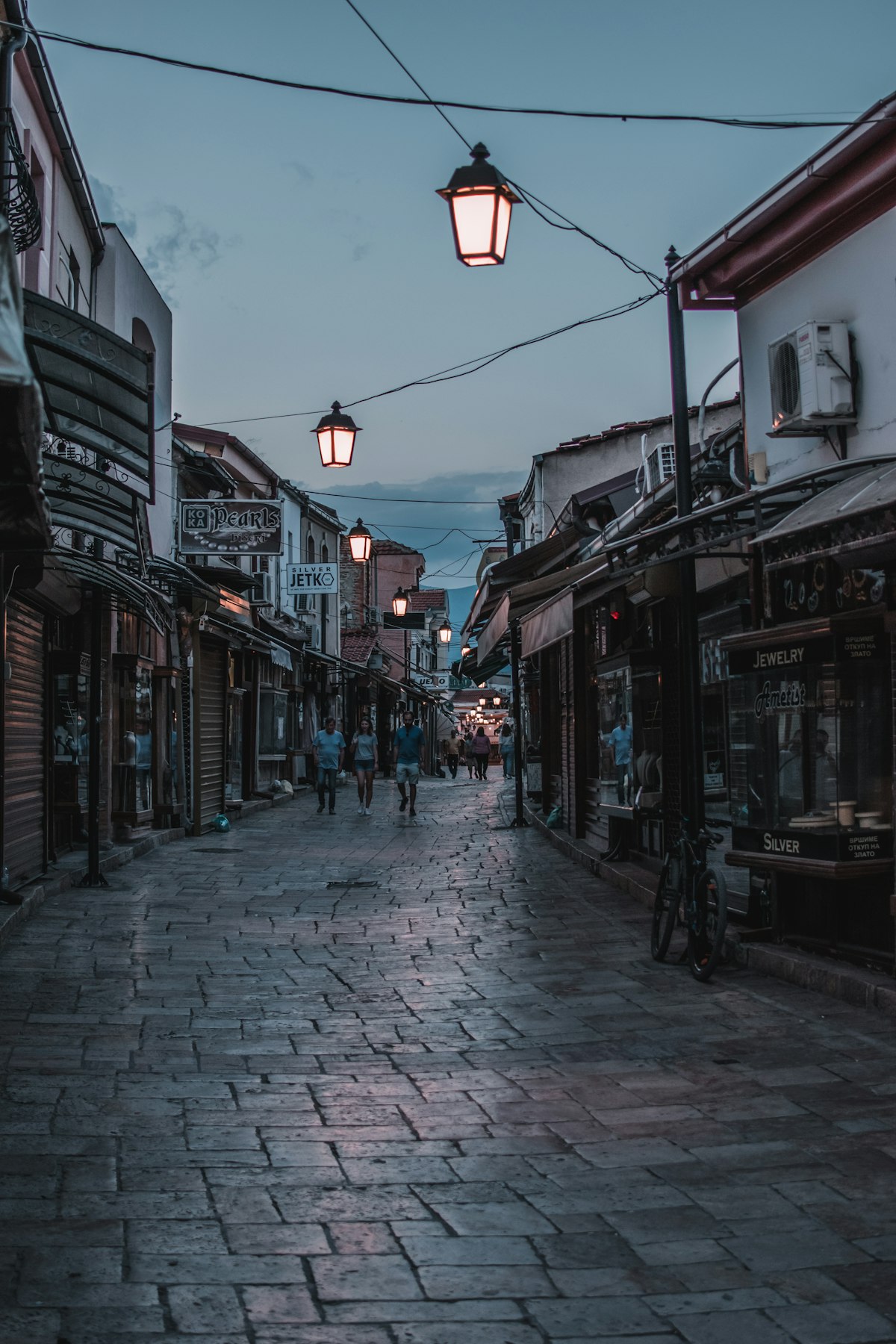 Cobblestone street of Skopje Old Bazaar with glowing lanterns at dusk, North Macedonia