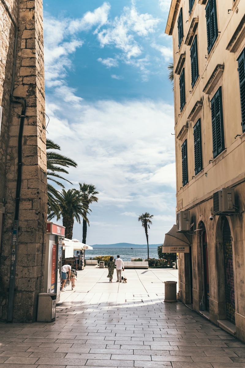 People walking past stone buildings in Split, Croatia