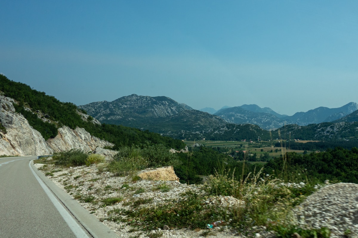 Mountain road through green hills approaching the Albania-Montenegro border
