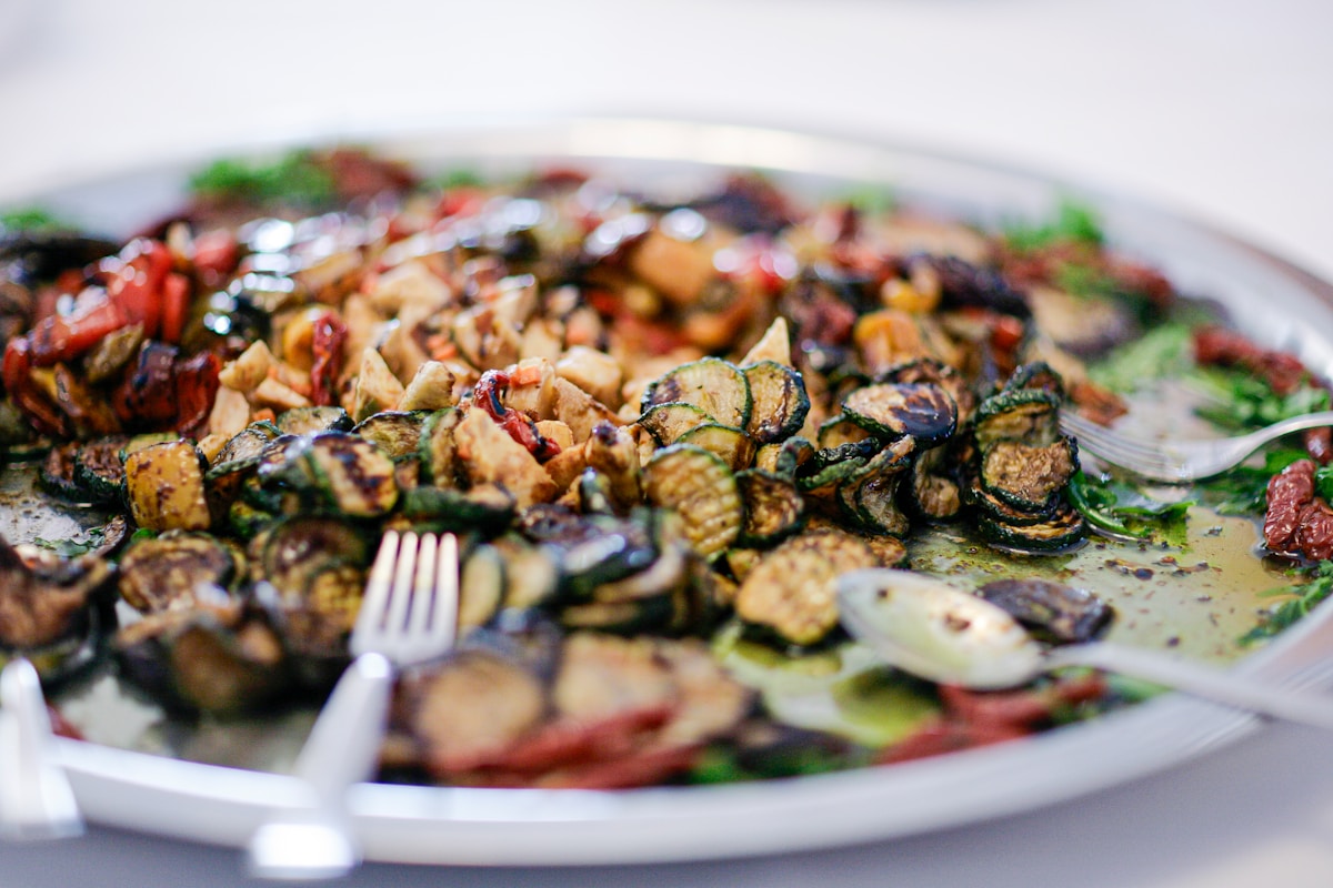 A platter of grilled vegetables including courgette, aubergine, and peppers with herbs