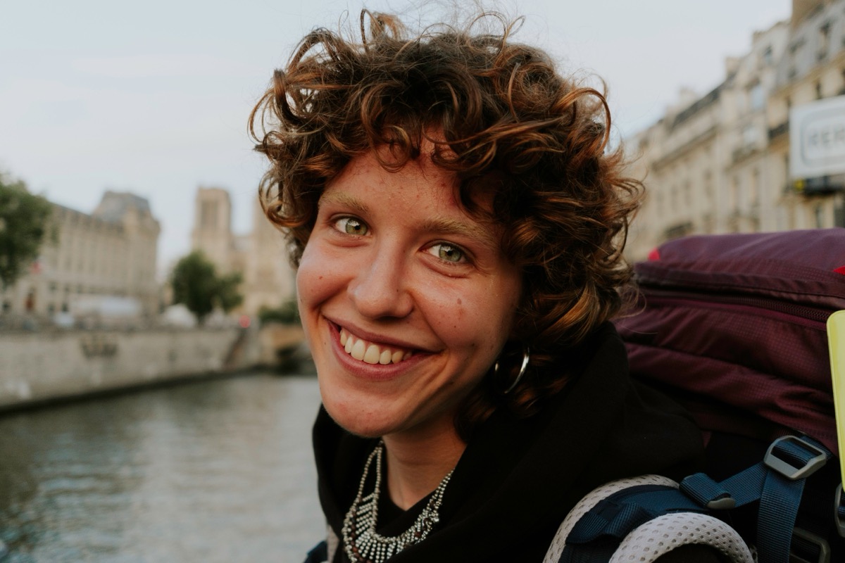 Young backpacker with a large rucksack smiling near a European river canal