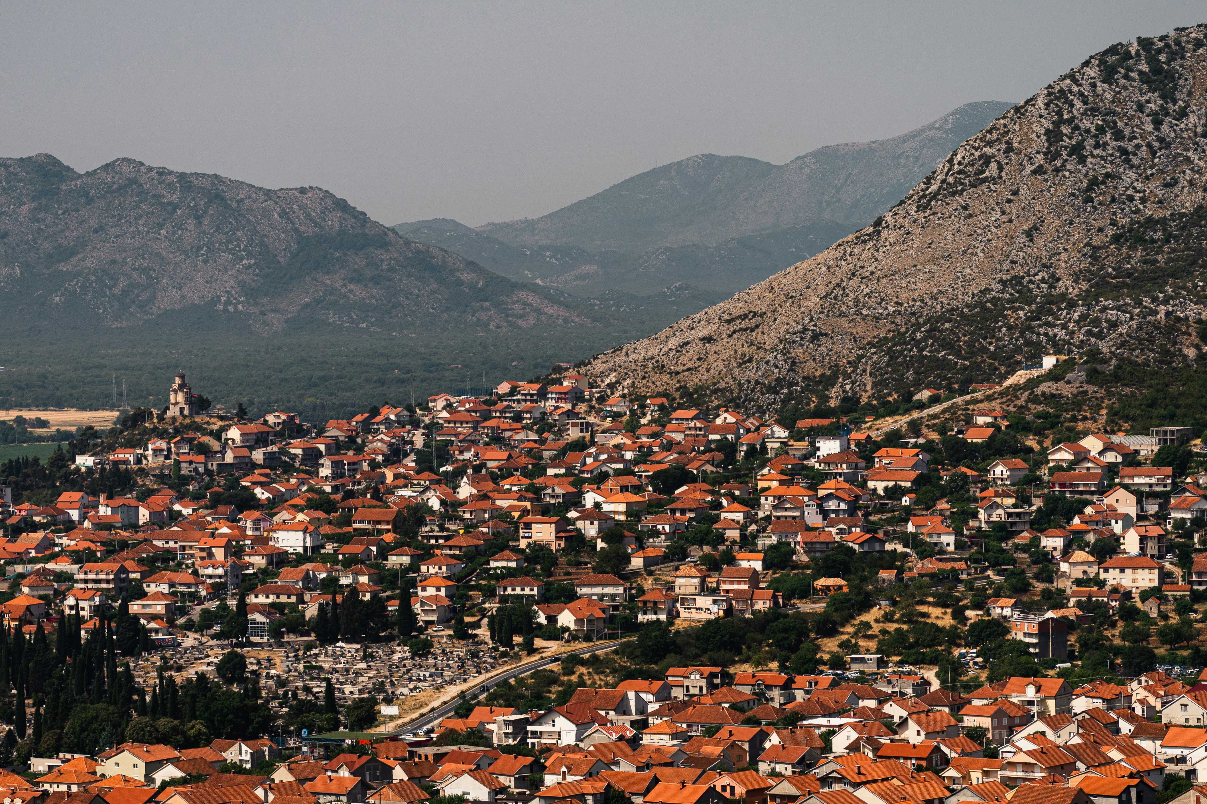 Panoramic view of Trebinje with orange-roofed houses and rocky mountains behind, Bosnia