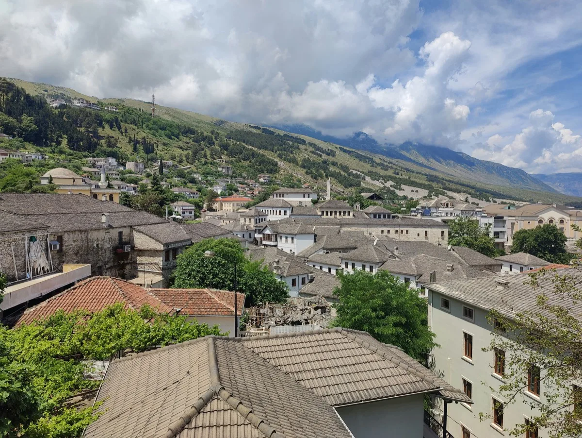 Stone-roofed Ottoman houses climbing the hillside in Gjirokastra, Albania, with the castle visible above